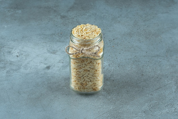 Foto grátis grãos de macarrão em uma jarra de vidro com fundo azul. foto de alta qualidade