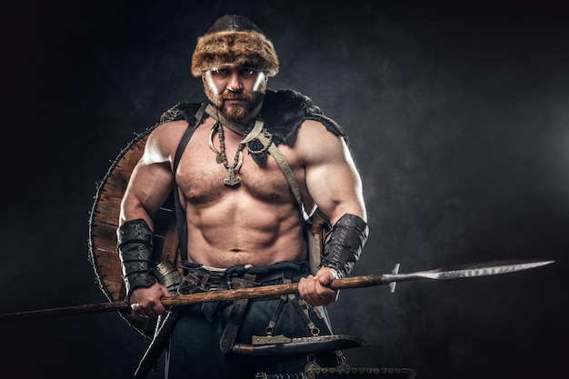 Foto grátis grave bárbaro em roupas de guerreiro, posando em um fundo escuro.