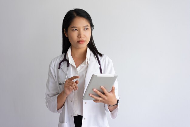 Grave jovem médico feminino usando computador tablet