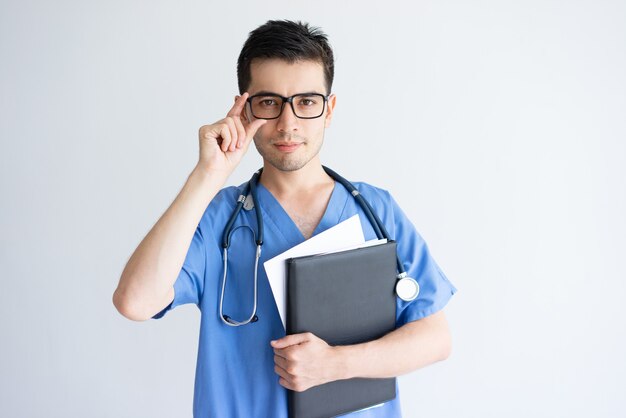 Grave jovem médico masculino segurando a pasta e documentos