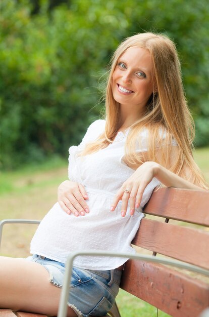 gravidez de cabelos longos mulher sentada no parque de verão