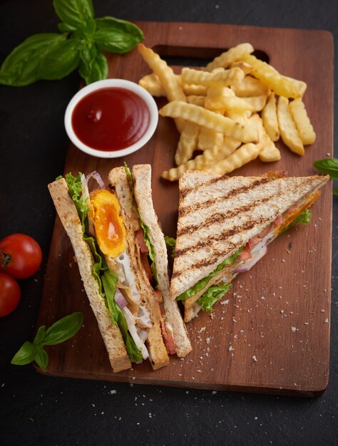 Grelhado e sanduíche com bacon, ovo frito, tomate e alface servido em tábua de madeira