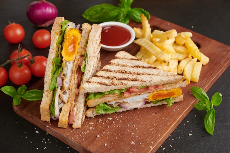 Foto grátis grelhado e sanduíche com bacon, ovo frito, tomate e alface servido em tábua de madeira