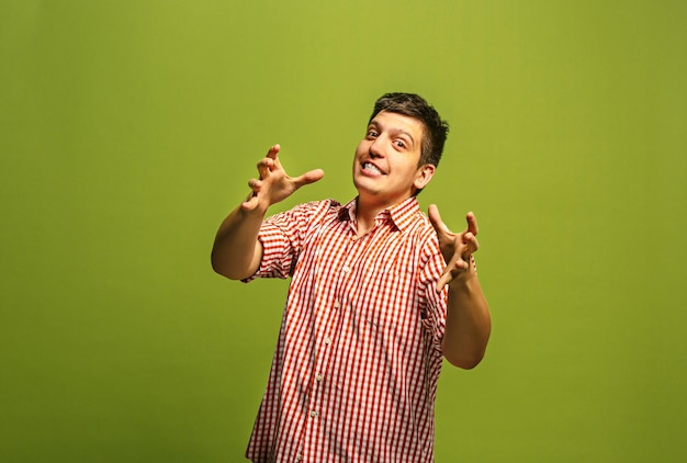 Foto grátis gritos, ódio, raiva. chorando homem zangado emocional, gritando sobre fundo verde do estúdio. rosto jovem e emocional. retrato de meio corpo masculino.