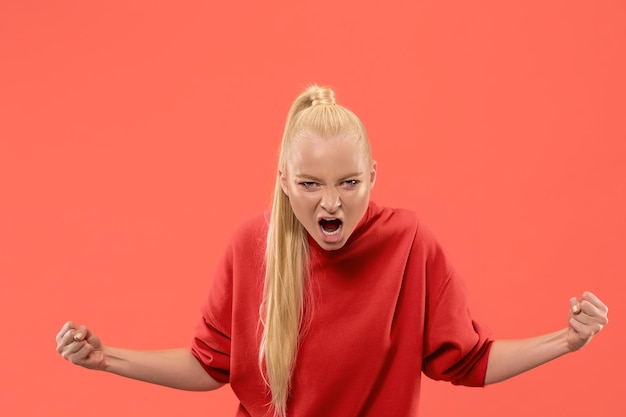 Foto grátis gritos, ódio, raiva. mulher com raiva emocional chorando gritando no fundo do estúdio de coral. rosto jovem e emocional. retrato feminino de meio corpo. emoções humanas, conceito de expressão facial. cores da moda