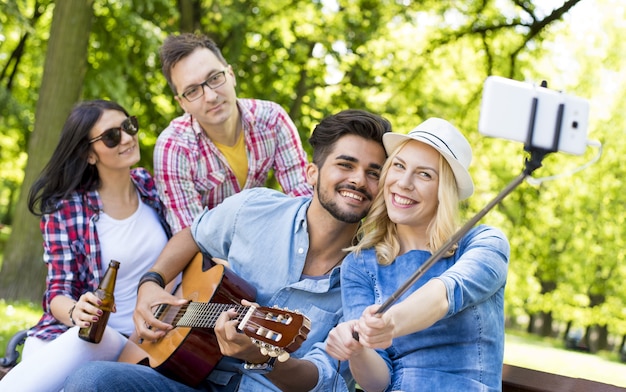 Grupo alegre de amigos caucasianos tirando uma selfie com um bastão de selfie