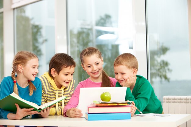 Grupo de alunos olhando para laptop na sala de aula