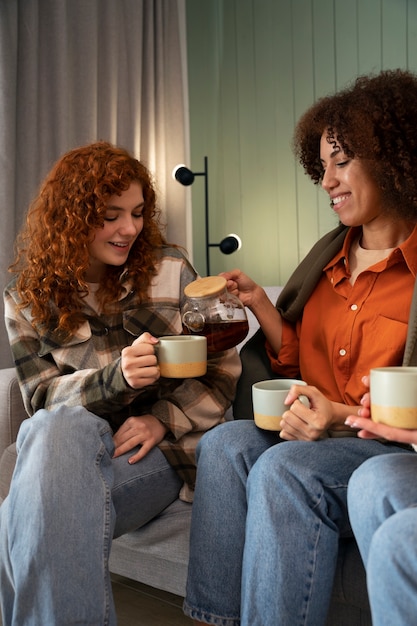 Grupo de amigas assistindo esportes em casa e tomando uma bebida