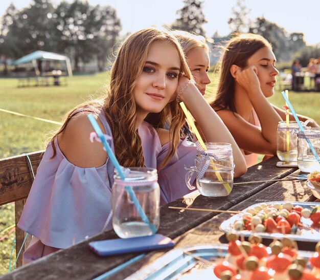 Grupo de amigas sentadas à mesa juntas comemorando um aniversário no parque ao ar livre.