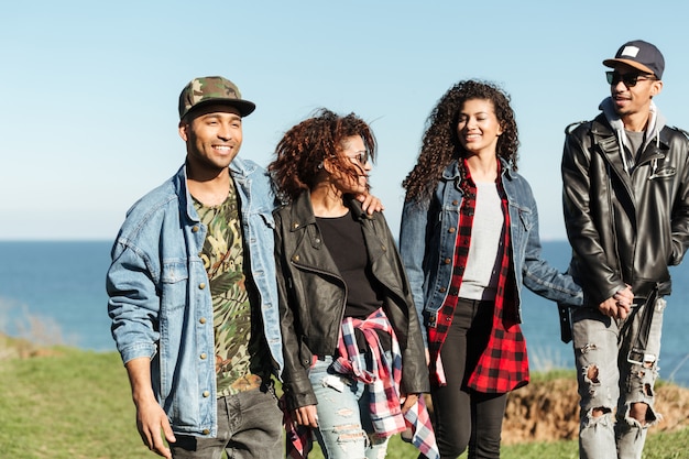 Grupo de amigos africanos caminhando ao ar livre perto da praia.