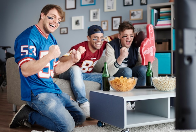 Grupo de amigos assistindo futebol em casa