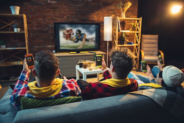 Grupo de amigos assistindo tv, jogo de esporte juntos. fãs emocionais torcendo pelo time favorito, assistindo futebol emocionante. conceito de amizade, lazer, emoções.