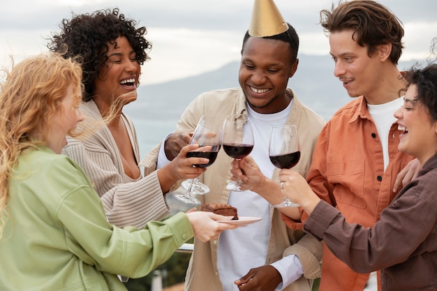 Grupo de amigos brindando com taças de vinho durante festa ao ar livre