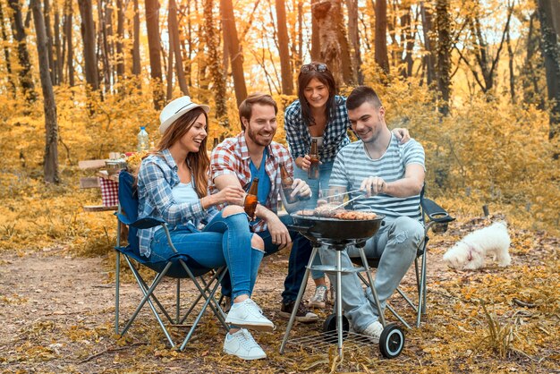 Grupo de amigos caucasianos fazendo churrasco e se divertindo na floresta