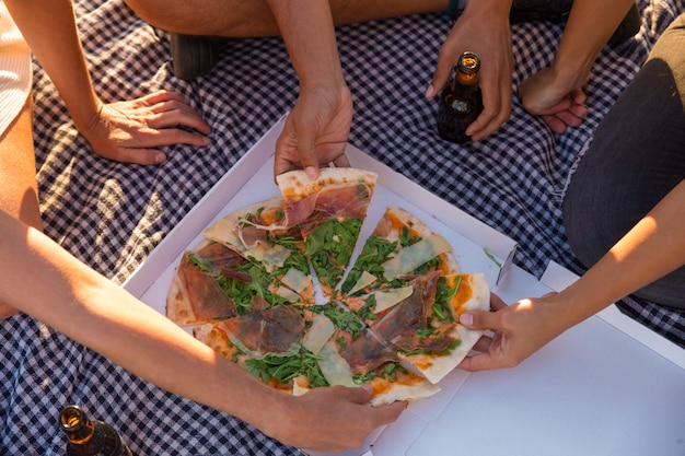 Grupo de amigos comendo pizza ao ar livre