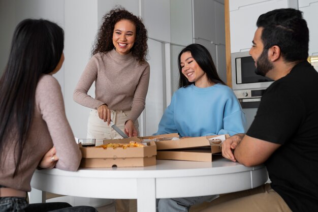 Grupo de amigos comendo pizza juntos em casa