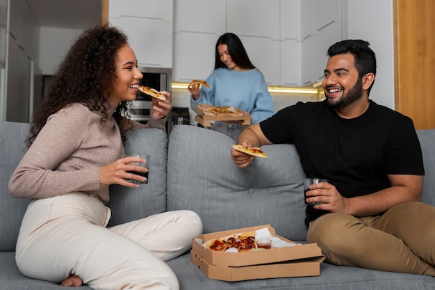 Grupo de amigos comendo pizza juntos em casa