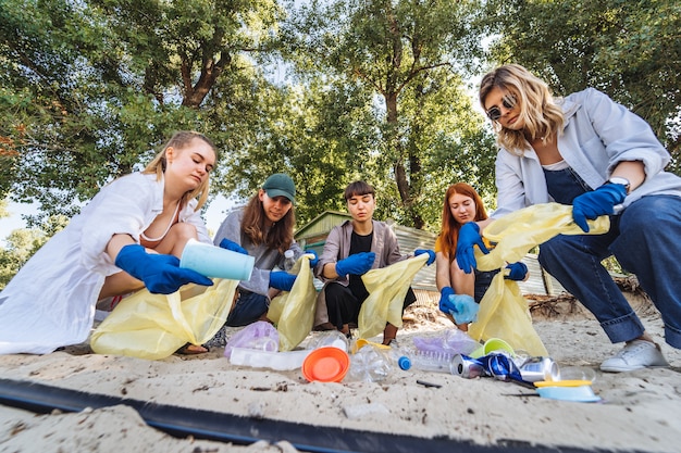 Grupo de amigos de ativistas que coletam resíduos plásticos na praia. Conservação ambiental.