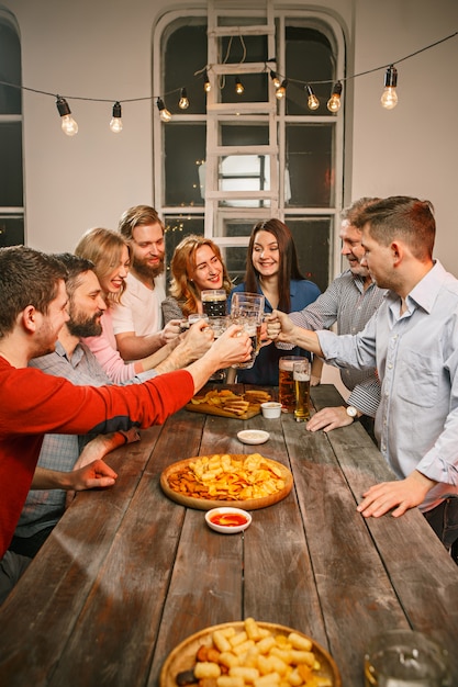 Foto grátis grupo de amigos, desfrutando de bebidas à noite com cerveja na mesa de madeira