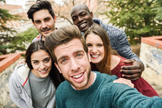 Grupo de amigos felizes que tomam uma foto