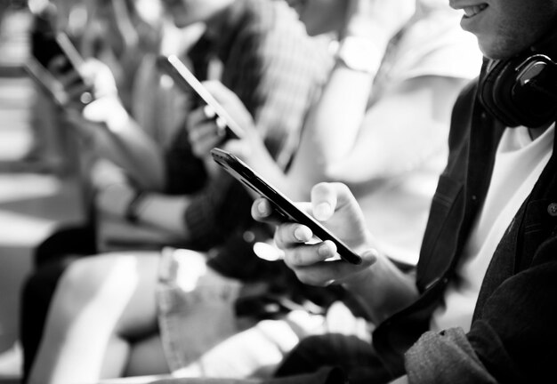 Grupo de amigos jovens adultos usando smartphones no metrô