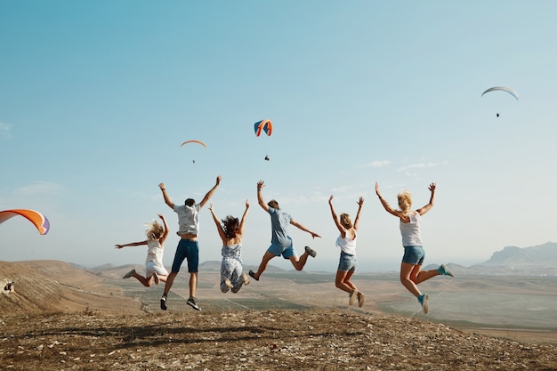 Foto grátis grupo de amigos pulando no topo de uma colina