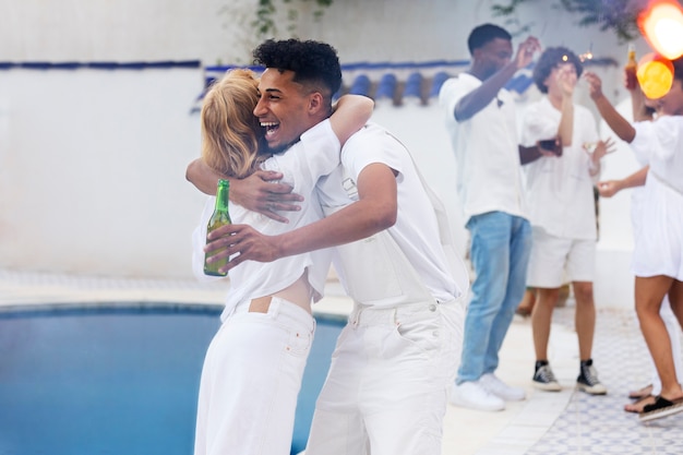 Grupo de amigos se divertindo durante uma festa branca com bebidas à beira da piscina