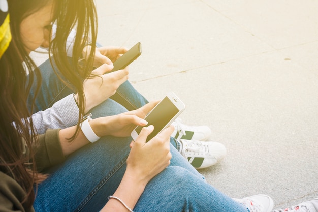 Foto grátis grupo de amigos sentados ao ar livre usando smartphone