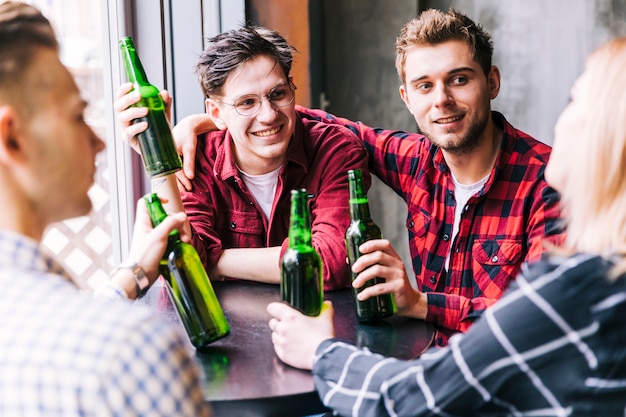 Grupo de amigos sentados ao redor da mesa, apreciando a bebida no restaurante pub