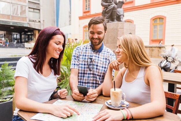 Grupo de amigos sentados no restaurante à procura de direção no smartphone