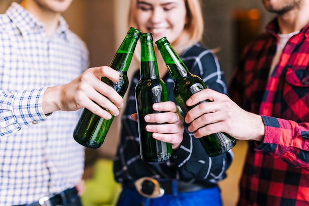 Grupo de amigos tinindo garrafas de cerveja no pub