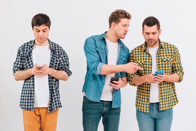 Grupo de amigos usando telefone celular contra o pano de fundo branco