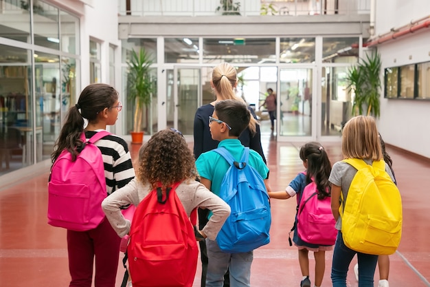 Foto grátis grupo de crianças com professora caminhando no corredor da escola