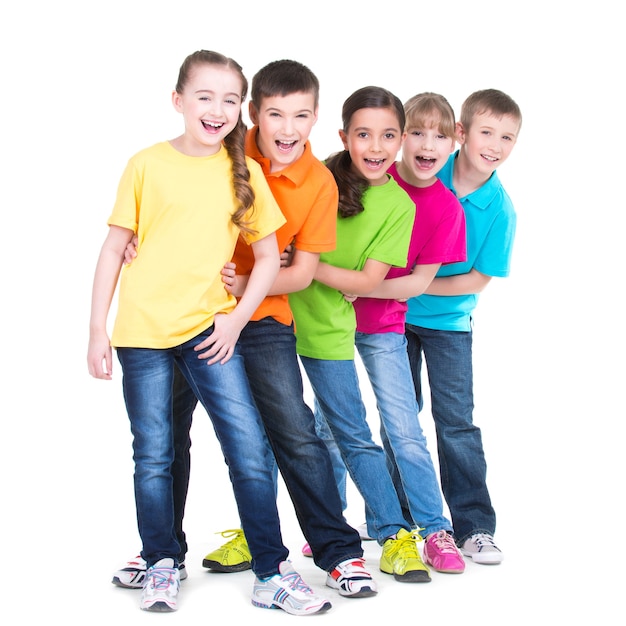 Grupo de crianças felizes em camisetas coloridas fica atrás uns dos outros no fundo branco.