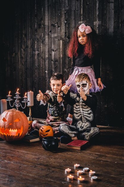 Grupo de crianças multirraciais fofas em trajes assustadores durante a festa de Halloween em uma casa velha. Conceito de dia das bruxas.