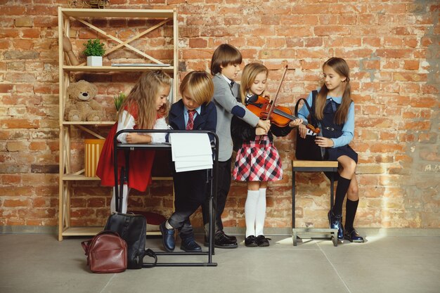 Grupo de crianças que passam um tempo juntos depois da escola. Amigos bonitos descansando depois das aulas antes de começar a fazer a lição de casa. Interior moderno do sotão. Tempo escolar, amizade, educação, conceito de união.