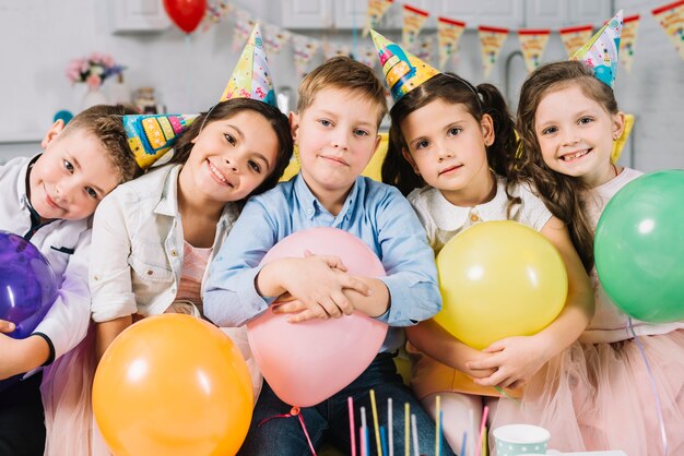 Grupo de crianças segurando balões coloridos durante o aniversário