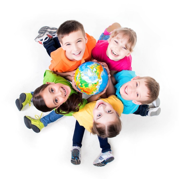 Grupo de crianças sorridentes, sentadas no chão em um círculo com um globo nas mãos - isolado no branco.