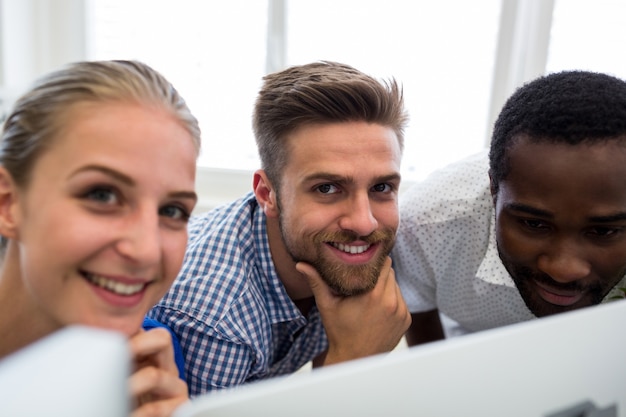 Grupo de designers gráficos, sorrindo, enquanto trabalha no computador