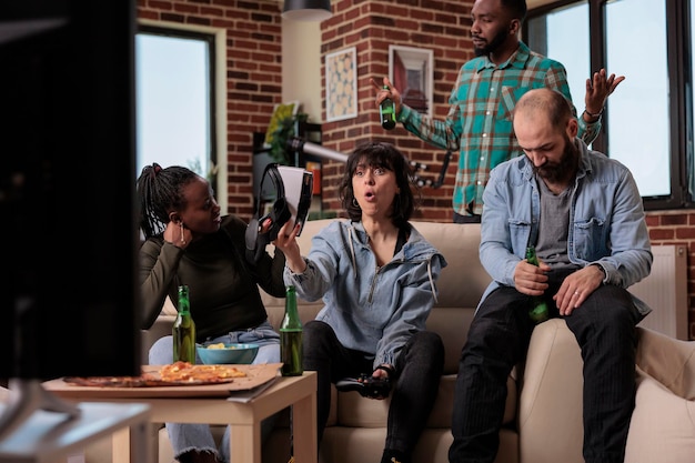 Foto grátis grupo de diversos amigos se sentindo tristes com o jogo perdido de videogame, usando óculos vr e console de tv para se divertir com o jogo de competição. pessoas se reunindo em festa divertida, perdendo o jogo juntos.