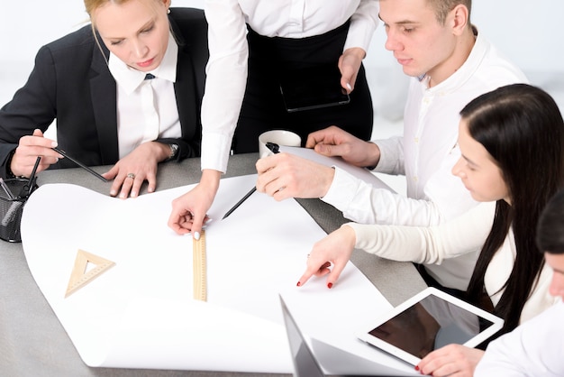 Grupo de empresário e empresária, planejando o projeto em papel sobre a mesa