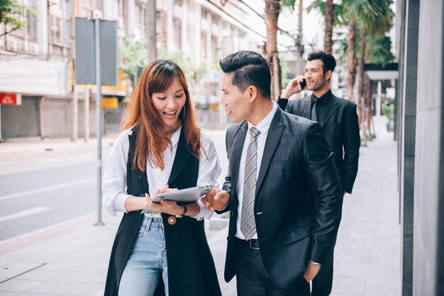 Grupo de empresários asiáticos no distrito de negócios falando sobre novos negócios e economia no local ao ar livre