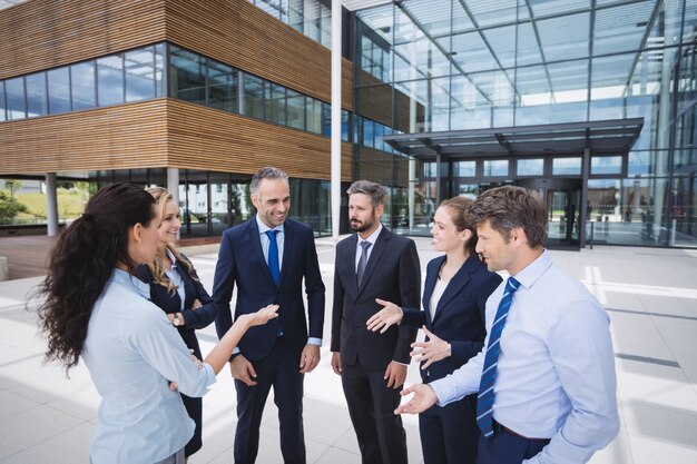 Grupo de empresários interagindo fora do prédio de escritórios