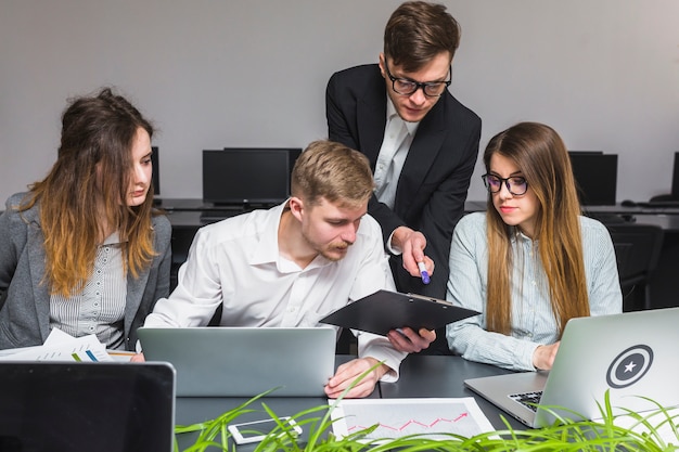 Foto grátis grupo de empresários usando laptop enquanto trabalhava no documento