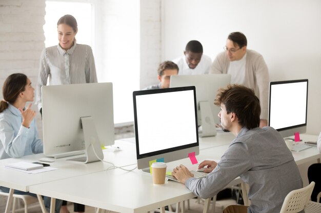 Grupo de funcionários corporativos diversos trabalhando juntos usando computadores no escritório