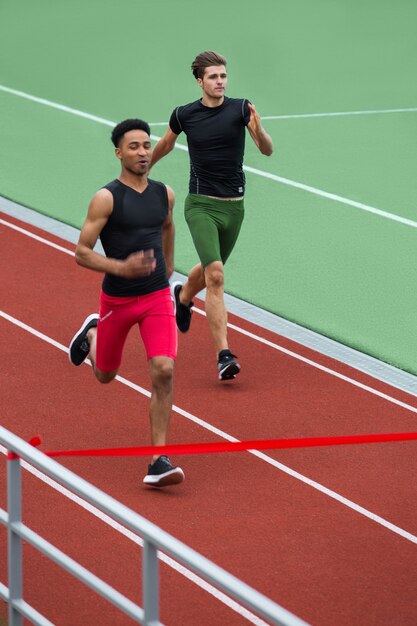 Grupo de homens atletas correr na pista de corrida ao ar livre