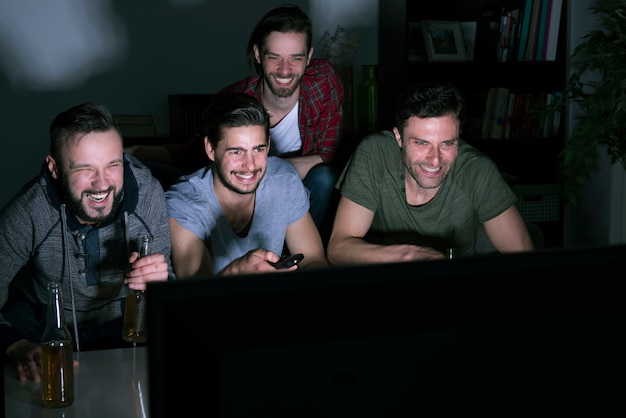 Grupo de homens bebendo cerveja e assistindo futebol na TV