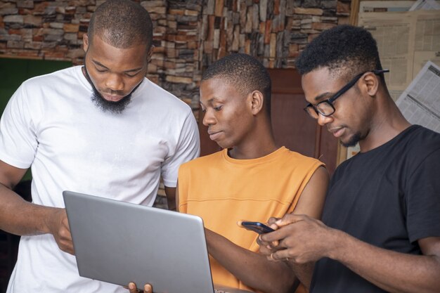 Grupo de jovens africanos discutindo um projeto enquanto usam seus laptops e telefones