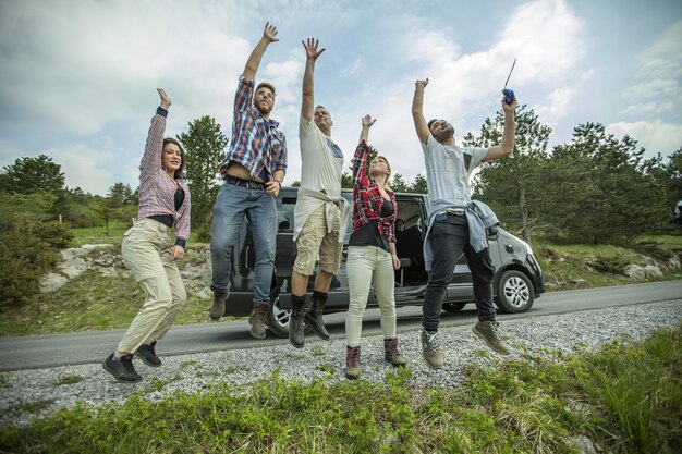 Grupo de jovens amigos alegres pulando e se divertindo ao ar livre na estrada