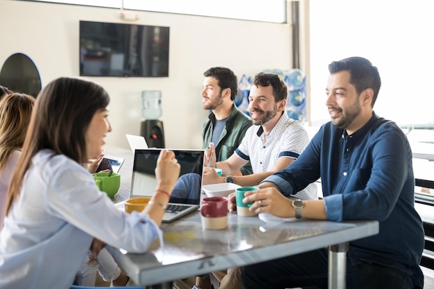 Grupo de jovens colegas de trabalho com comida e bebida no refeitório